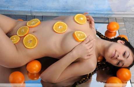 Solo girl Sofie tugs on her pigtails before covering her naked body in oranges
