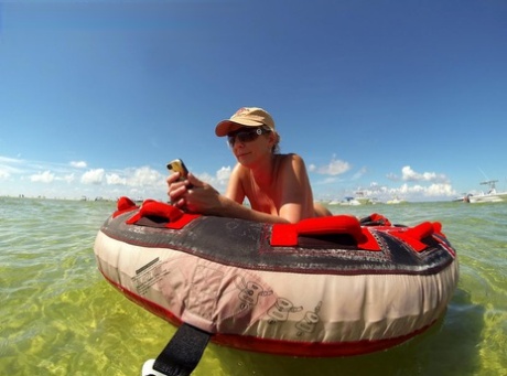 Big titted amateur lounges on an air mattress while naked in a ball cap