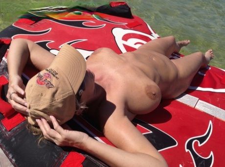 Big titted amateur lounges on an air mattress while naked in a ball cap