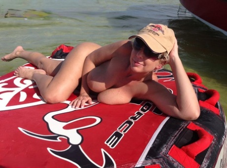 Big titted amateur lounges on an air mattress while naked in a ball cap