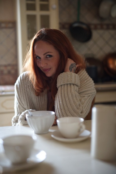 UK redhead Kara Carter rubs cream into her big natural tits in the kitchen