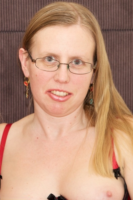 Mature lesbians have sexual relations on a bed in hosiery and glasses